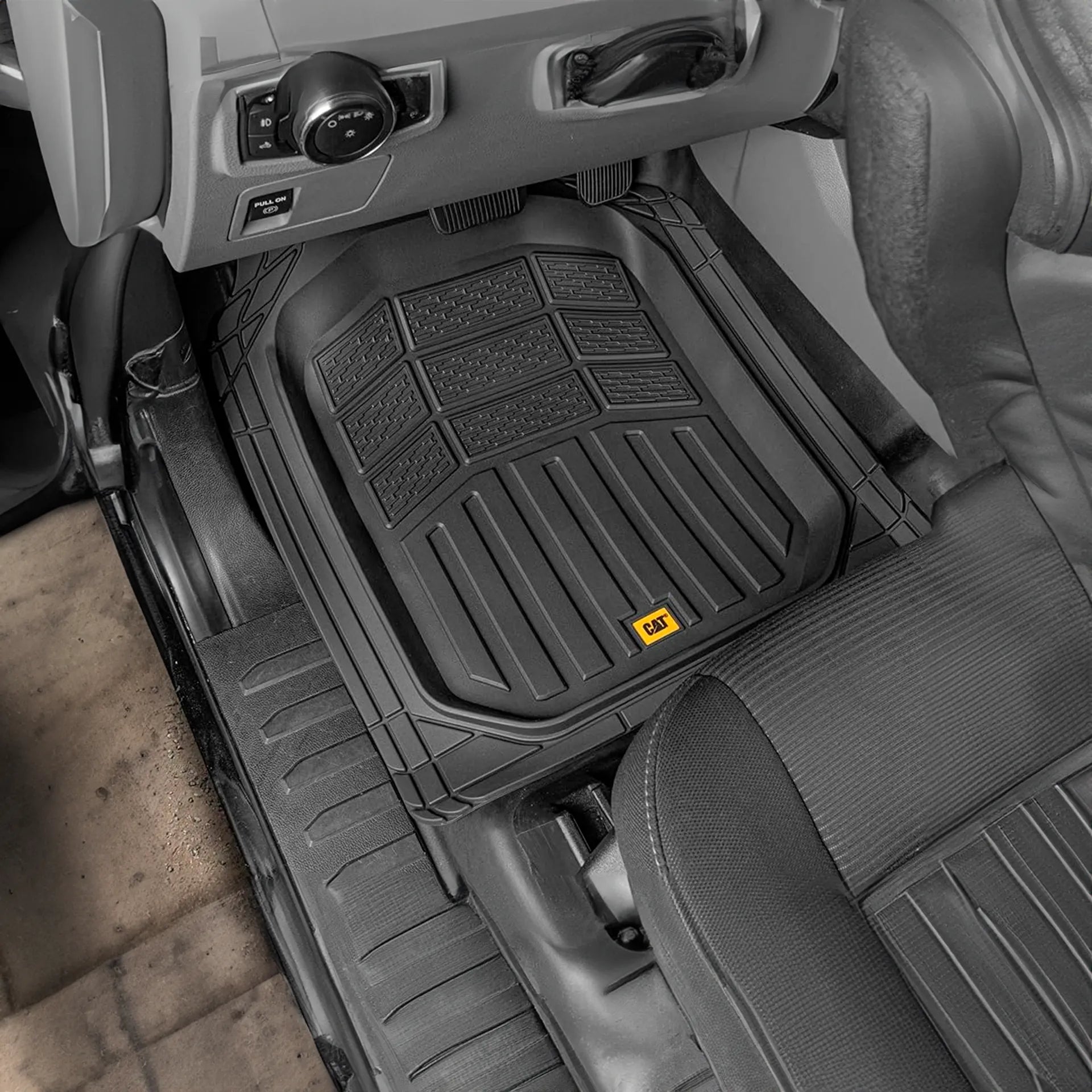 Tapete de hule negro de uso rudo marca CAT instalado en el piso del asiento de un vehículo.