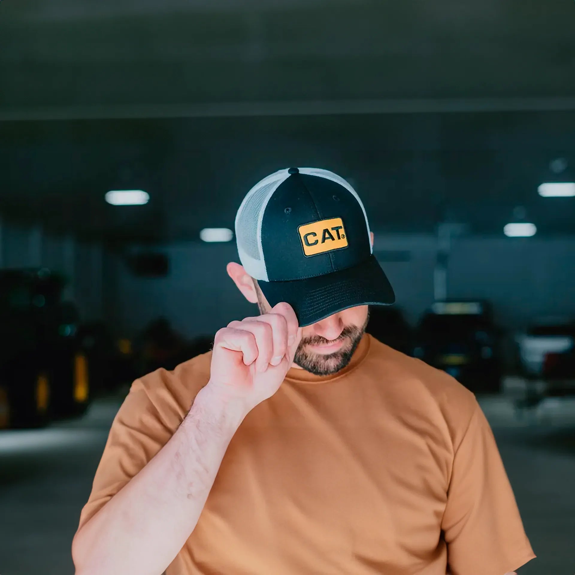 Hombre con gorra trucker Caterpillar negra con blanco.