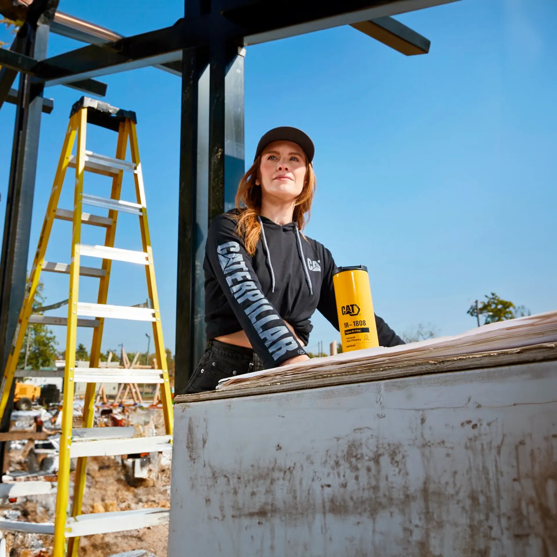 Mujer con sudadera de manga larga negra y cilindro Caterpillar.